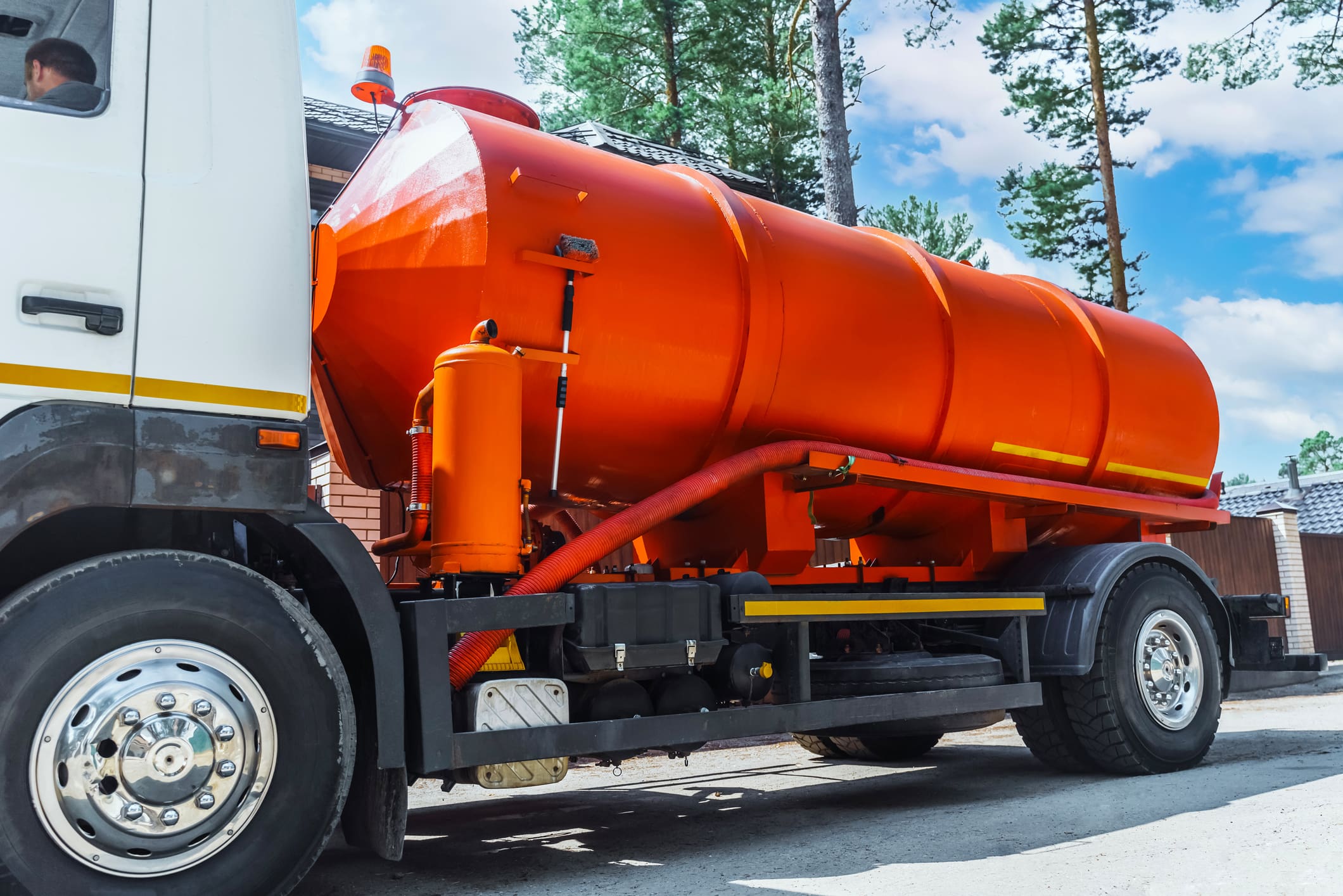 Bright orange tanker truck near trees